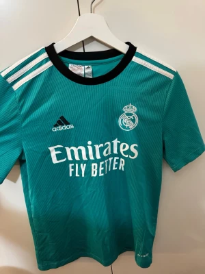 Real Madrid adidas fotbollströja - Snygg Real Madrid fotbollströja från adidas i turkos med vita och svarta detaljer. Storlek S men passar även XS