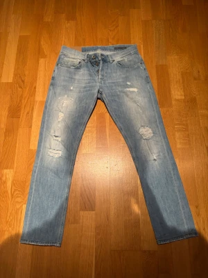 Dondup George 33 - Ljusblåa jeans med fabriksslitningar. Jeansen har lapp inutt i där det står 34 i stl men mått 43 cm så snarare 32/33. 
