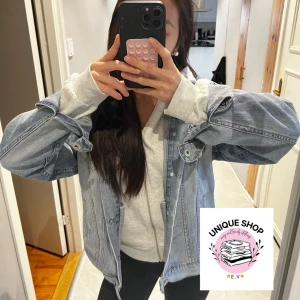 Oversized ljusblå jeansjacka - Säljer en oversized ljusblå jeansjacka med klassiska detaljer som bröstfickor med knappar och knappstängning framtill. Jackan har en avslappnad passform och är perfekt att slänga över en hoodie för en chill look. Strlk: L men passar xs