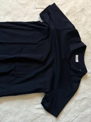 Mörkblå polotopp/pike från NN.07 i XL - Jättefin stilren mörkblå polotopp/pike från NN.07 i storlek XL. Toppen har klassisk krage och korta ärmar, tillverkad i mjuk 100% bomull som är väldigt mjuk och skön. Den är i bra skick, inga fläckar eller nått sånt. Den är dessutom i bra kvalité, passar till mycket och är perfekt till garderoben som ett basplagg. Skriv om funderingar, lämna gärna omdöme och priset kan diskuteras😊