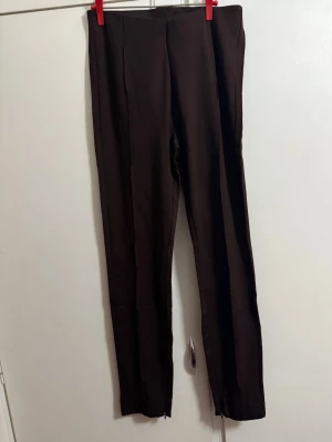 Bruna kostymbyxor från Stories M - Snygga bruna kostymbyxor från Stories i storlek M. Byxorna har en rak och slim passform med hög midja och är tillverkade i ett mjukt material som ger en stilren look. Perfekta att matcha med en enkel topp eller skjorta för en clean vibe.