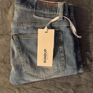 Ljusblå jeans från Dondup, storlek 32 - Snygga ljusblå jeans från Dondup i klassisk femficksmodell. Jeansen har en rak passform och är tillverkade i mjukt bomullsdenim. Perfekta för dig som gillar stilrena och tidlösa jeans med italiensk design.