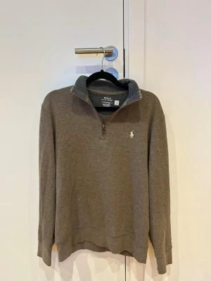 Halvzip från Ralph lauren - Säljer då den ej kommer till användning. St S men liten i storlek sitter perfekt på dig runt 174 cm plus minus några cm. Väldigt snygg tröja man kan klä upp eller bara ha som daglig tröja i skolan ex. Väldigt fint skick bara lite skrynklig pga ej använt men det tas lätt bort vid användning!! Färgen är typ brun/beige/grön