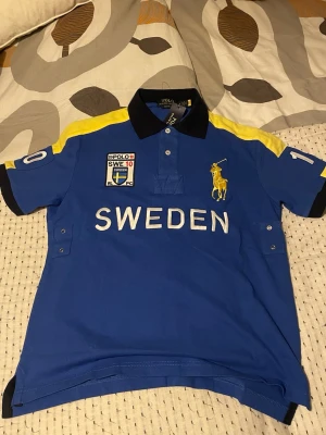 Polo Ralph Lauren Sweden piké - Säljer en blå piké från Polo Ralph Lauren med SWEDEN-tryck och nummer 10 både fram och bak. Tröjan är i chief keef stil och bara allmänt soft.  Tröjan har använts endast ett fåtal gånger och alltid med tagsen på.  Om du har fler frågor är det bara skicka ett meddelandet! 