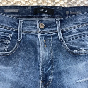 Replay Anbass - Säljer ett par Replay Anbass Hyperflex jeans i blå tvätt med snygga slitningar och klassiska fem fickor. Jeansen har stretchigt material som gör dem riktigt bekväma. Perfekt för dig som gillar en modern och stilren look. Pris kan diskuteras! OBS hål lite över vänstra ficka men inte så märkvärdigt går och fixa 