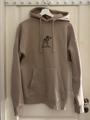 Beige hoddie från pull&bear - En beige hoodie från pull&bear med en tryck på bröstet(tror det ska föreställa en indian) och med en text på ena armen. Den är stor i storlek då det är en man storlek