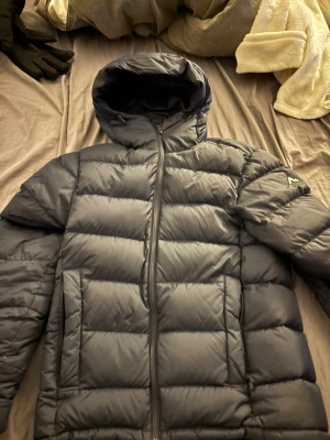 Svart pufferjacka från McKinley XS - Säljer en mörkblå vinter jacka  från märket McKinley i storlek X small . Jackan har huva, dragkedja framtill och breda, quiltade paneler. Perfekt för kalla dagar och riktigt skön att bära. Klassisk look med diskret logga på ärmen.