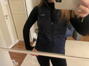 Väst från Patagonia - Snygg mörkblå dunväst från Patagonia i storlek XS. As snygg, men tyvärr förliten för mig. Nästan helt oanvänd och i ett jättebra skick. Perfekt att slänga över en hoodie eller långärmad tröja när det är kyligt ute. Cirka 1400kr nypris. 