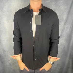 Burberry skjorta svart  - En burberry skjorta perfekt för just dig som vill klä dig med en bra stil. Inga defekter och är i storlek xl men sitter som en L. Vid frågor och funderingar kom dm. Pris kan diskuteras vid snabbaffär