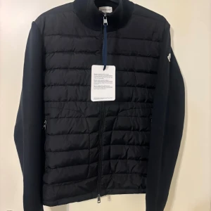 Moncler cardigan - Moncler cardigan – svart, storlek M Helt ny och aldrig använd. Fick den i present men den passar tyvärr inte, därför säljer jag den vidare. Perfekt kvalitet och sitter snyggt. Nypris är högt, så passa på!