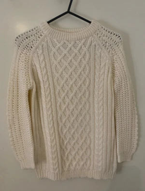 Vit stickad tröja från Zara Knit - Säljer en vit stickad tröja från Zara Knit i storlek S. Tröjan har ett snyggt flätmönster framtill och grovstickade detaljer på ärmar och axlar. Rund halsringning och långa ärmar ger en klassisk look. Perfekt för dig som gillar chunky knitwear.