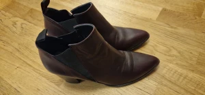 Mörkbruna skinnstövletter med klack *Rizzo - Snygga mörkbruna stövletter i skinn med spetsig tå och låg klack. De har elastiska paneler på sidorna för enkel påtagning och en stilren, smal siluett. Perfekta för dig som gillar en klassisk men edgy look.