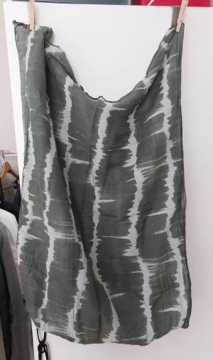 Batiksjal från STANK - Snygg och luftig halsduk från STANK i en mix av bomull och silke. Den har ett randigt mönster i grönt och vitt, perfekt för att ge din outfit en cool touch. Tillverkad i Italien och känns riktigt skön mot huden.