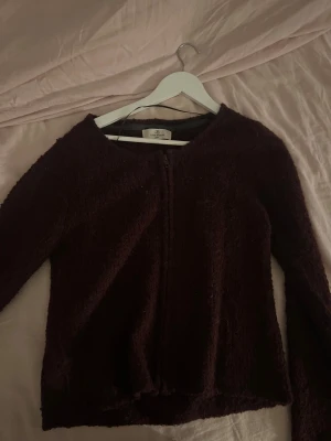 Mörkbrun teddyjacka från Flash Woman - Mysig mörkbrun teddyjacka från Flash Woman i storlek L. Jackan har en enkel design med rund hals och dragkedja framtill. Materialet är fluffigt och ger en skön känsla, perfekt för kyliga dagar. Långärmad och med en loose passform.