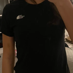 Svart t-shirt från The North Face XS - Svart t-shirt från The North Face i storlek XS. Klassisk rund hals och korta ärmar. Logotypen finns både fram och bak i vitt. T-shirten är gjord i mjuk bomull och har en clean, normal passform som funkar till allt.