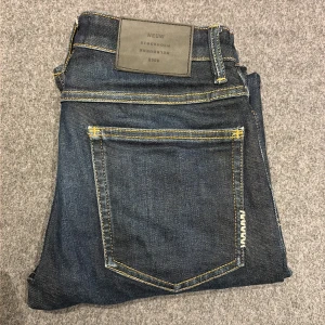Mörkblå jeans från Neuw - Snygga mörkblå jeans från Neuw med klassisk femficksdesign och kontrasterande gula sömmar. Modellen har rak passform och normal midja, med en stilren läderpatch bak i midjan. Perfekta för dig som gillar enkel och tidlös denimstil. Nypris 1800