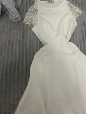 Vit klänning med spetsdetaljer NELLY - Supersöt vit klänning från NELLY i kort modell med spets på axlarna. Klänningen har en rund halsringning och är figurnära upptill med en lätt utsvängd kjol. Materialet känns mjukt och har en elegant look, perfekt för dig som gillar romantiska detaljer.