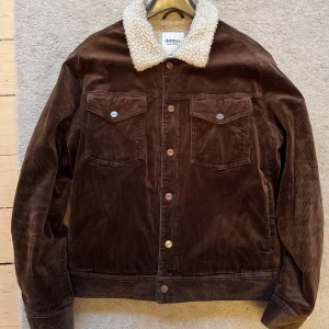 Brun teddyjacka från Dobber - Säljer en brun teddyjacka från Dobber i manchester med fluffigt vitt foder och krage. Jackan har två bröstfickor med knappar, knappstängning framtill och en schysst retrovibe. Perfekt för dig som gillar chill och varm stil under höst och vinter.