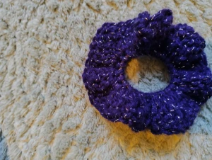 Lila glittrig virkad scrunchie - En snygg lila scrunchie med glittriga inslag virkad av mig. Perfekt accessoar för att piffa upp din frisyr med lite extra bling och färg.