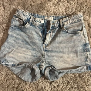 Ljusblå jeansshorts från Lindex - Snygga ljusblå jeansshorts från Lindex med klassisk femficksdesign, knapp och dragkedja framtill. Shortsen har en högmidjad passform och stl 158/xxs. 