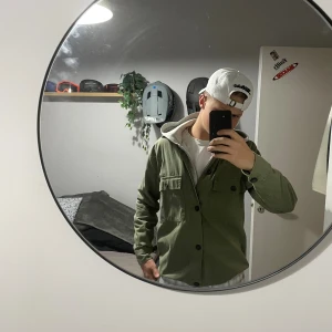 Grön overshirt med knappar - Säljer en stilren grön overshirt  bomull. Jackan har klassisk krage, två bröstfickor med lock och knappar framtill. Perfekt att slänga på över en hoodie eller t-shirt för en chill look. Passar dig som gillar enkel och clean stil.