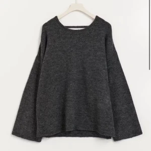 Mörkgrå stickad tröja med öppen rygg - Snygg mörkgrå stickad tröja med långärmad passform . Aldrig använd tidigare alltså i hel nytt skick, prislappen är dock inte kvar