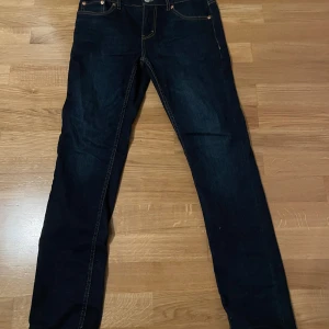 Levi's 512 Slim Taper jeans mörkblå - Snygga Levi's 512 Slim Taper jeans i mörkblå tvätt med klassiska kontrastsömmar och fem fickor. Modellen har smal passform och avsmalnande ben, perfekt för dig som gillar en modern siluett. Ikonisk Levi's patch baktill och metallnitar vid fickorna.