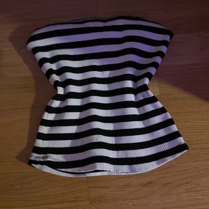 Randig bandeau tubtopp från H&M - Säljer en svartvit randig bandeau tubtopp från H&M i storlek S. Toppen är ribbad och ärmlös med en tight passform som sitter snyggt över kroppen. Perfekt för dig som gillar enkel och stilren design med lite edge. Säljer på grund av att den inte kommer till användning. Kontakta för fler frågor💓