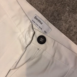 Vita kostymbyxor från Bershka - Snygga vita kostymbyxor isch från Bershka med rak passform och klassisk midja. Byxorna har knapp och dragkedja fram samt en ficka med knapp bak💓💓
