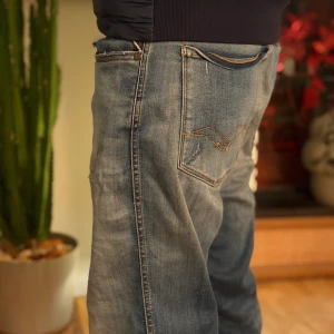 Replay ljusblå jeans med broderade fickor - Säljer ett par ljusblå jeans från Replay med snyggt slitna detaljer och broderade bakfickor. Jeansen har klassisk femficksdesign, raka ben och normal passform. Materialet är mjukt denim i bomull och de har Replay-logga vid fickan.