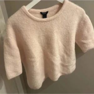 Ljusrosa stickad tröja från Lindex - Supermjuk och fluffig ljusrosa stickad tröja från Lindex. Tröjan har korta ärmar och rund halsringning