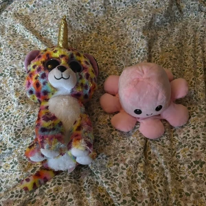 Ty Beanie Boo Fantasia & Reversible Octopus Plush - Säljer en färgglad Ty Beanie Boo Fantasia enhörning med glittrigt horn och stora ögon, samt en rosa vändbar bläckfisk med glad och arg ansikte. Båda är mjuka, i fint skick och perfekta som present eller samlarobjekt. Inga synliga defekter eller slitage.