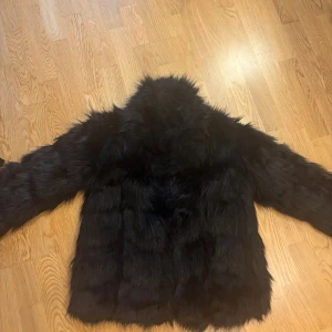 Svart pälsjacka från My Trend - Säljer en svart pälsjacka med fluffig och mjuk känsla. Jackan har långärmade ärmar och är helsvart med en snygg, lite oversized passform. 