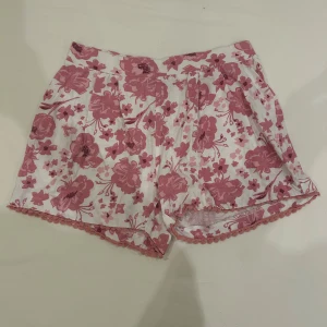 Blommiga shorts från Mywear i S - Säljer ett par söta pyjamas shorts från Mywear med rosa blommigt mönster på vit botten. 