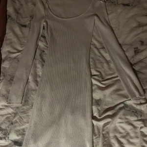 Ribbad vit kortklänning FB Sister - Supersnygg ribbad vit kortklänning från New Yorker  med lång ärm och fyrkantig ringning. Klänningen är tight och stretchig, perfekt för dig som gillar en enkel men stilren look. Materialet är mjukt och följsamt, vilket gör den riktigt bekväm att bära. Jag är ca 166