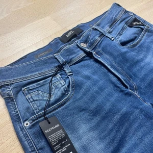 Blå Replay Anbass Hyperflex jeans - Snygga blå jeans från Replay, modell Anbass Hyperflex. Jeansen har klassisk femficksdesign, normal passform och raka ben. Materialet är stretchigt för extra komfort och rörelsefrihet. Perfekta för dig som vill ha stilrena och bekväma jeans med modern känsla. Storlek 32/32