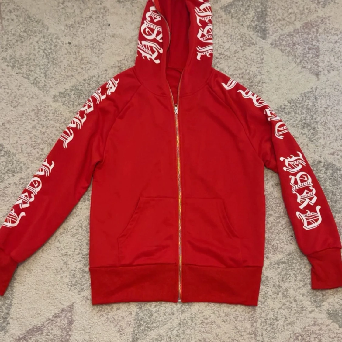 Röd hoodie med vita tryck och dragkedja