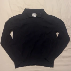 Svart merinoull piké tröja These Glory Days - Säljer en svart pikétröja från These Glory Days i mjuk och lyxig merinoull. Tröjan har klassisk krage och lång ärm, perfekt för lager-på-lager under kyliga dagar. Enkel och stilren design som funkar till allt. Storlek S men sitter mindre