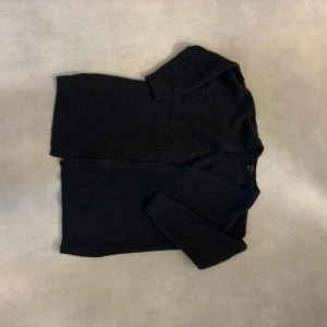 Svart stickad kofta från Esmara - Svart stickad kofta från Esmara i storlek L. Koftan har långärmade ribbade ärmar och öppen front utan knappar. Materialet är mjukt och grovstickat, perfekt för att hålla värmen under kyliga dagar. Enkel och stilren design som funkar till många olika outfits. Lite nopprig.