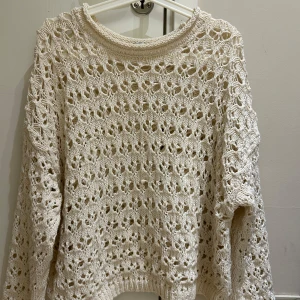 Beige stickad tröja från Stradivarius - Säljer en beige stickad tröja från Stradivarius i storlek L. Tröjan har ett luftigt, hålmönstrat stickat material och långa ärmar. Perfekt för lager-på-lager och ger en chill vibe till din outfit. Kan även använda Stl S och M 