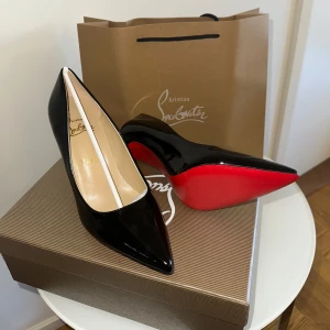 Christian Louboutin svarta pumps - Ikoniska svarta pumps från Christian Louboutin i lackat skinn med klassisk röd sula. Skorna har spetsig tå och hög klack, vilket ger en elegant och edgy vibe. Perfekta för dig som vill sticka ut med exklusiv design och lyxig känsla. SKORNA ÄR ALDRIG ANVÄNDA!