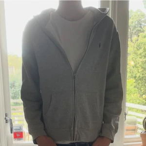 Grå hoodie från Polo Ralph Lauren XL - Grå hoodie från Polo Ralph Lauren i storlek  XS. Säljer på grund av att den är för liten. Lite sliten på ett ställe på dragkedjan men märks inte av vid användning. Passar om man är 160-170.  Det är bara att höra av sig vid minsta fundering🙌