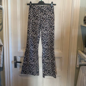 Leopardmönstrade strechtights, flare - Säljer ett par snygga flare byxor med leopardmönster i svart och beige. Byxorna har hög midja och är tillverkade i ett mjukt syntetmaterial som sitter skönt. Perfekta för dig som vill sticka ut med ett djuriskt coolt print.