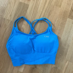 Sport-BH från ICANIWILL - Säljer en blå ribbad sporttopp från ICANIWILL med smala korsade axelband i ryggen. Aldrig använd. 