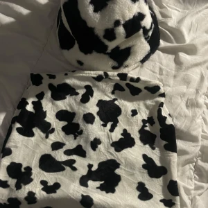 En kjol och bucket hat med koskinnsmönster - Säljer en fluffig bucket hat och en n kjol som ett set. Hatten har rund form och är fodrad med svart tyg på insidan. Perfekt statement-piece för dig som vill sticka ut med en trendig accessoar.