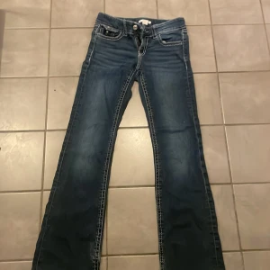 Blå bootcut jeans från Gina Tricot - Snygga blå jeans från Gina Tricot i bootcut-modell med markerade vita sömmar och klassiska fickor fram och bak. Jeansen har dragkedja och knapp. Ganska välanvända så DMa för fler bilder🫶🏽💌