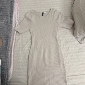 Beige ribbad kortklänning H&M - Superfin beige ribbad klänning från H&M med kort ärm och rund halsringning. Klänningen är figurnära, knappt använd.