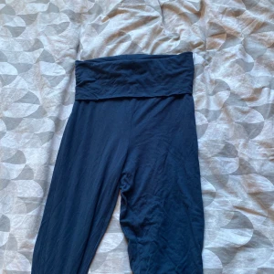 Mörkblå yoga pants från 157 XS - Mörkblåa yoga pants från 157 i storlek XS. Byxorna har hög midja men man viker ner överdelen av byxorna. Tillverkade i mjukt bomullsmaterial som är skönt mot huden. Perfekta för chill dagar eller när du vill ha det extra bekvämt.