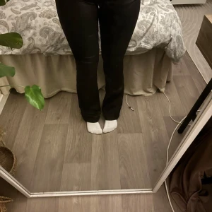 Svarta bootcut byxor med hög midja - Snygga svarta byxor med bootcut och hög midja. Byxorna har klassisk femficksdesign och sitter tight upptill med utsvängda ben. Perfekta för dig som gillar en stilren look med lite edge. Materialet är stretchigt och bekvämt.