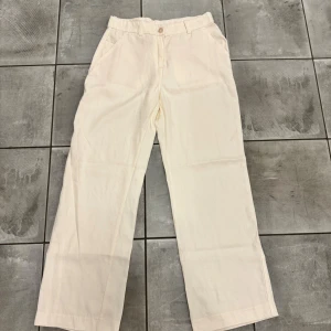 Vida vita byxor från H&M, stl 40 - Snygga vita byxor från H&M i storlek 40. De har raka, vida ben och klassisk midja med hällor för bälte. Byxorna är tillverkade i mjuk bomull och har fickor både fram och bak. Perfekta för en clean och stilren look.